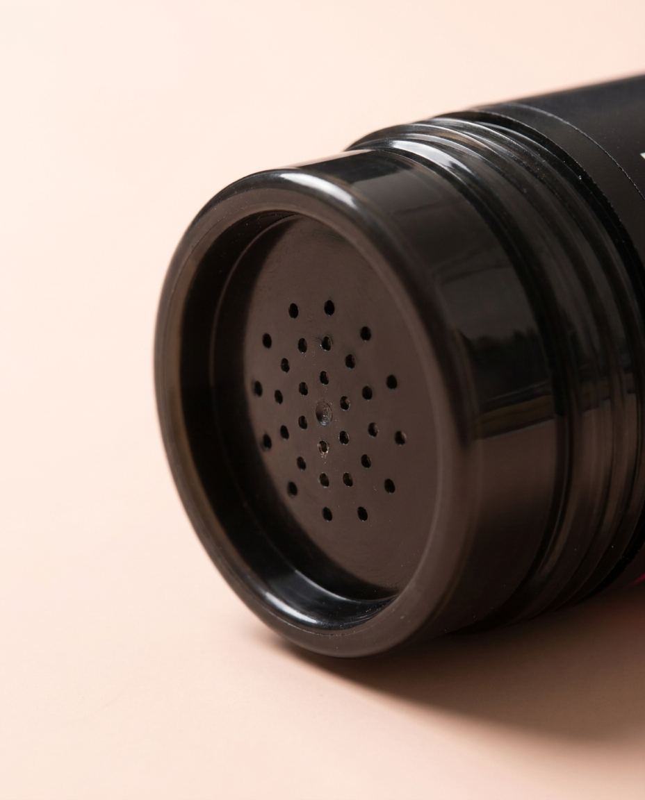 Keratin hair building fibers — close-up of sifter shaker cap on peach background