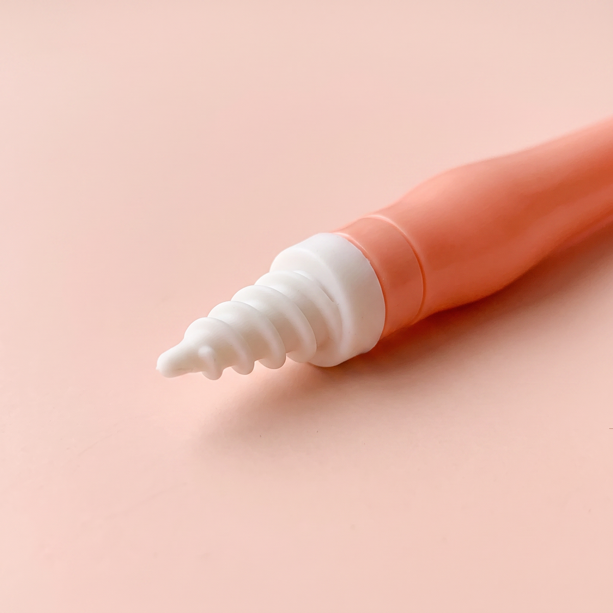 Spiral Ear Wax Remover — close-up of a spiral silicone tip on peach background